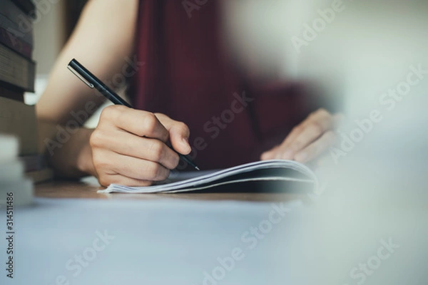 Fototapeta high school,university student study.hands holding pencil writing paper answer sheet.sitting lecture chair taking final exam attending in examination classroom.concept scholarship for education abroad