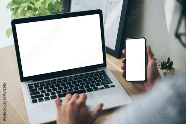 Fototapeta mockup image blank screen computer,cell phone with white background for advertising text,hand man using laptop texting mobile contact business search information on desk in office.marketing,design