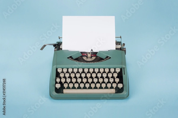 Fototapeta Retro old typewriter with paper on light blue background