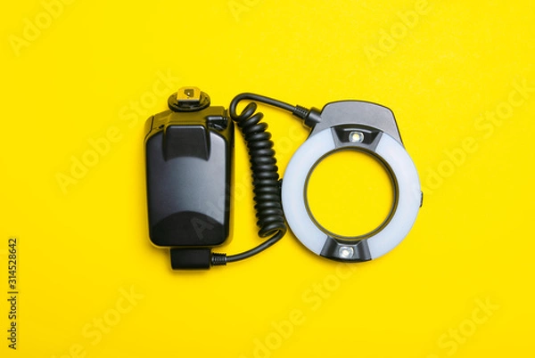 Fototapeta Ring flash on the camera on yellow background, top view