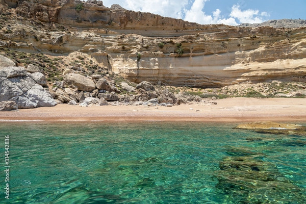Obraz View from a motor boat on the mediterranean sea on the rocky coastline with red sand beach and clear turquoise water near Stegna on the eastside of Greek island Rhodes