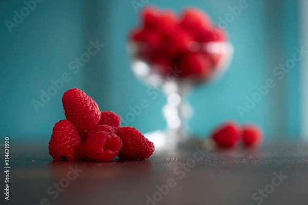 Obraz Ripe sweet raspberries on wooden table and blue background.