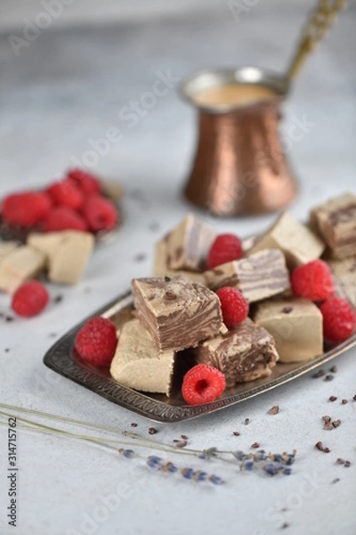 Fototapeta Oriental sweets, halva slices on a metal dish, decorated with raspberries, with Turkish coffee. Background, vertical.
