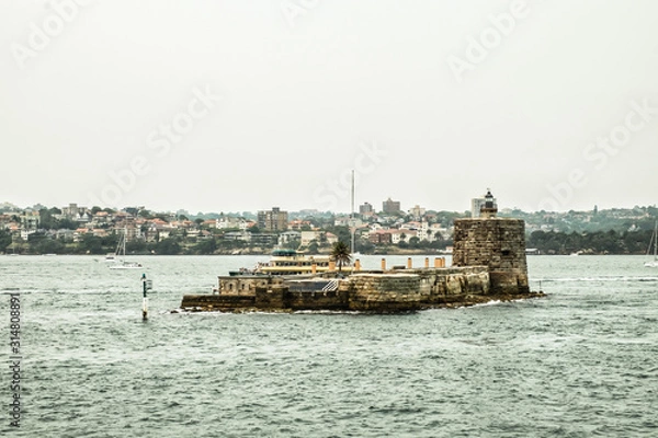 Obraz Brick island with small lighthouse floating on the water