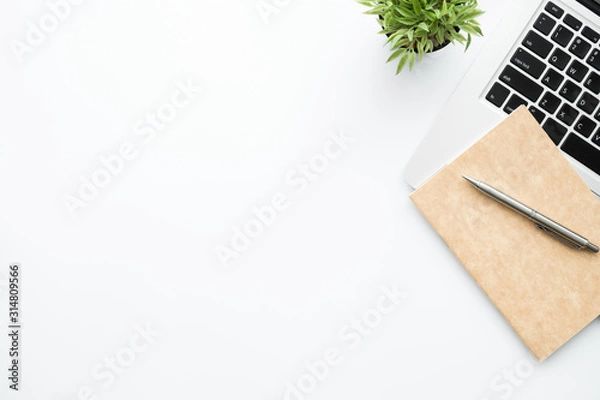 Fototapeta White office desk table with laptop computer and notebook with pen. Top view with copy space, flat lay.