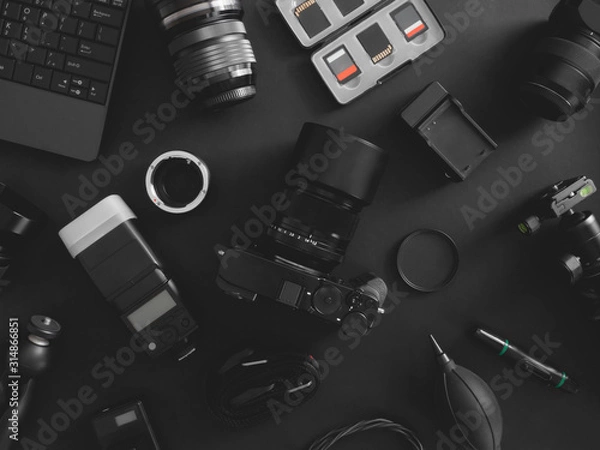 Fototapeta top view of work space photographer with digital camera, flash, cleaning kit, memory card, tripod and camera accessory on black table background