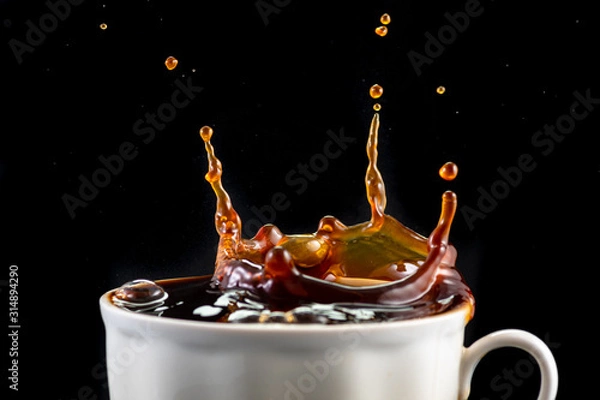 Fototapeta splash and splatter from a piece of sugar in a mug with coffee on a black background