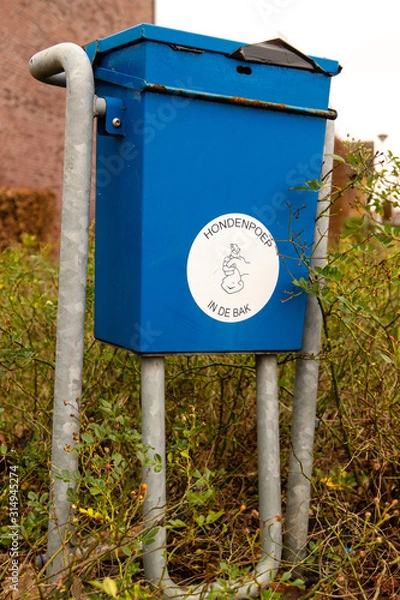 Fototapeta Garbage bin for dog poo in bleu color in a residential area in the Netherlands. Translation Hondenpoep in de bak: Dog poo in the bin.
