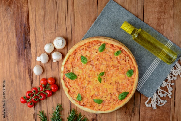 Fototapeta Colorful pizza ingredients: cherry tomatoes, basil, mushrooms, olive oil and pizza on wooden background. Copy space.
