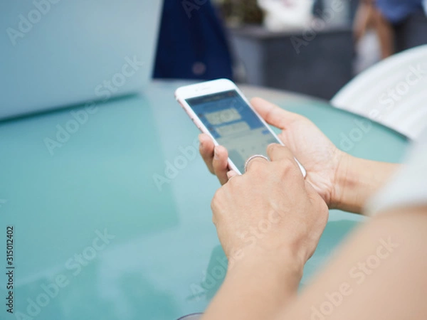 Fototapeta 外でスマートフォンを操作する女性