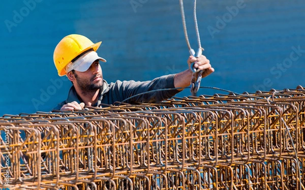 Obraz Construction worker loading stack of reinforcement beam cages to
