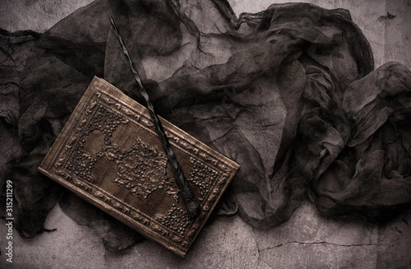 Fototapeta Old book with spells and magic wand on gray background with witch rag. Copy space for text