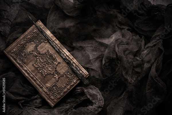 Fototapeta Old book with spells and magic wand on gray background with witch rag. Copy space for text