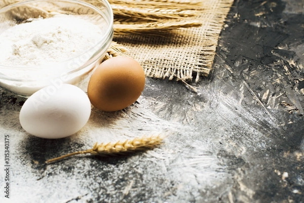 Obraz eggs and flour on wooden table. Baking background