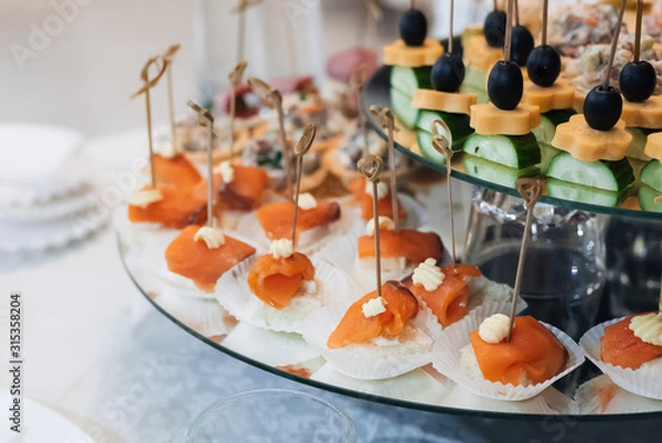 Fototapeta canapes with olives, cheese, cucumber and red fish for a delicious appetizer at a festive event