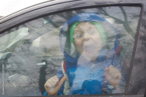 Fototapeta Little boy screams behind a car window