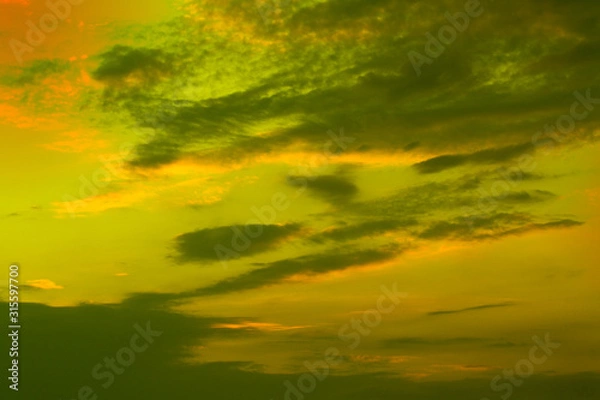 Obraz Sunset over green field and soft clouds.