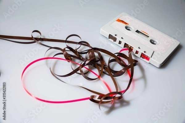 Obraz Leeds, UK, 03/02/19Cassette unspooled with loose tape tangled up around itself shot on isolated on a white background professionally with studio lighting and old retro vintage media unused now
