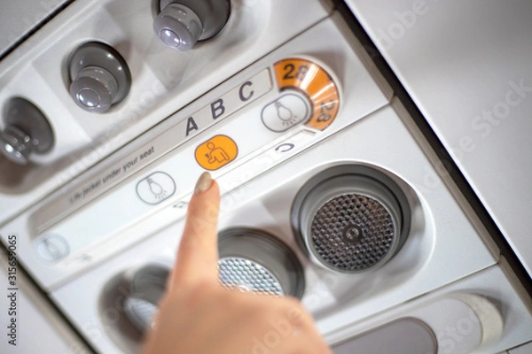 Fototapeta Female finger over flight attendant call button on airplane
