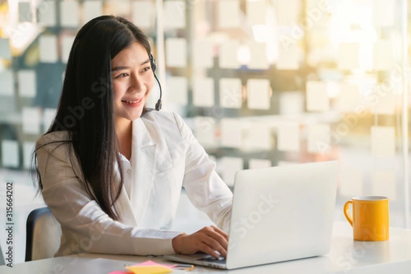 Obraz Young female customer support phone operator with headset working in call center.	