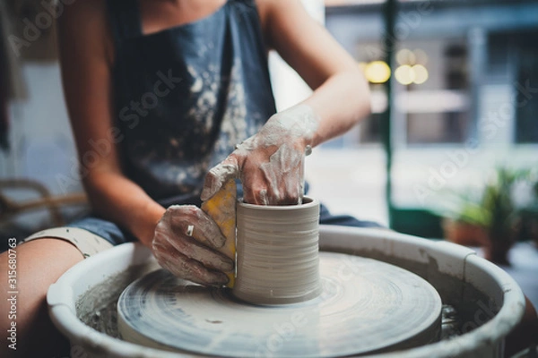 Obraz Cropped Image of Unrecognizable Female Ceramics Maker working with Pottery Wheel in Cozy Workshop Makes a Future Vase or Mug, Creative People Handcraft Pottery Class 