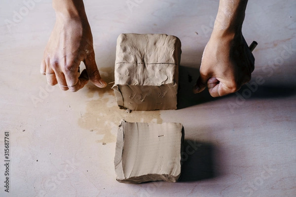 Fototapeta Female potter hands working with clay in workshop. White desk on background