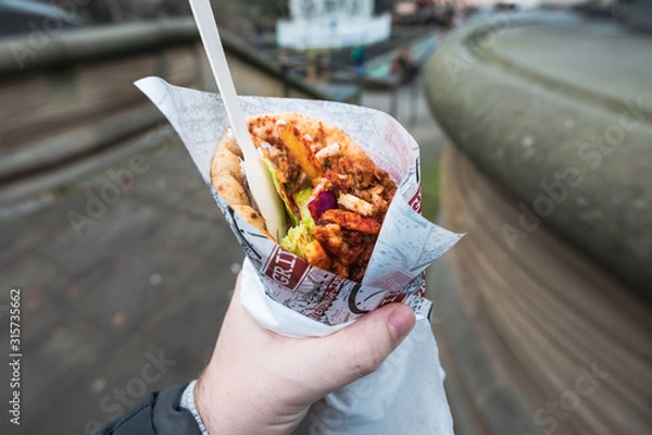 Fototapeta POV of a man holding and eating Gyro outside. Traditional Greek fast food