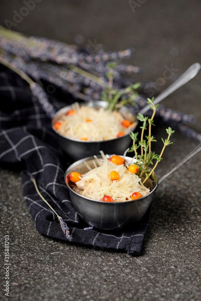 Obraz Festive french julienne with sea buckthorn in a bowl on napkin with bunch lavender on stone background. Rustic style. Baked mushroom julienne with chicken and cheese in pots. Top view. Close up