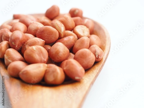 Obraz Peanut beans on wooden spoon and white wooden background, is a legume crop grown mainly for its edible seeds, Selective focus.
