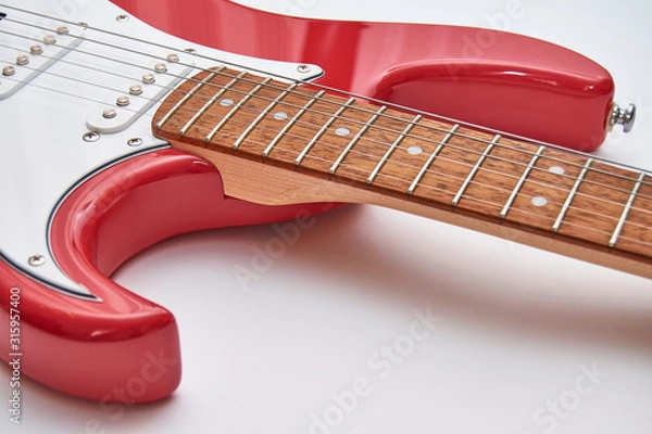 Fototapeta Fragment of a red electric guitar on a white background. Part of the guitar. Music object.