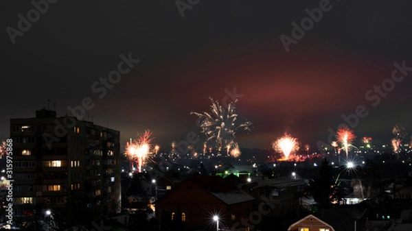 Fototapeta Night cityscape with lots of exploding holiday fireworks.