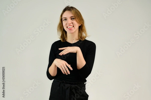 Fototapeta Portrait of a pretty blonde girl in a black t-shirt on a white background with emotions. A universal concept, the picture is suitable for any topic.