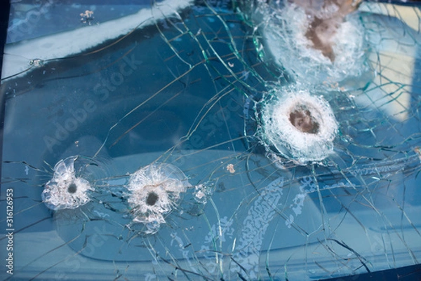 Fototapeta Bullet hole on a car windshield. Car window after a raid has a bullet hole. Broken glass. Bullet holes in a front windshield. Broken Windshield.