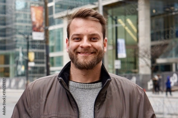 Fototapeta Man with a beard smiling in downtown Toronto with sky rise buildings in the background