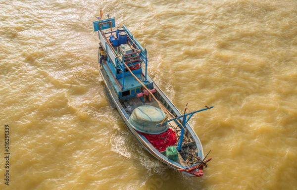 Obraz A small fishing boat is sailing in the sea for fishing. The photo was taken from above and from the side. Brown sea water due to the recent typhoon and many river sediments.