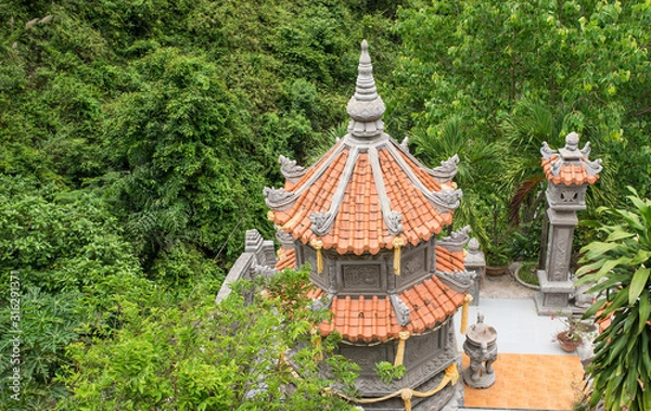 Obraz A small Buddhist pagoda that is hidden in the greenery of tall trees and dense bushes. Vietnam.