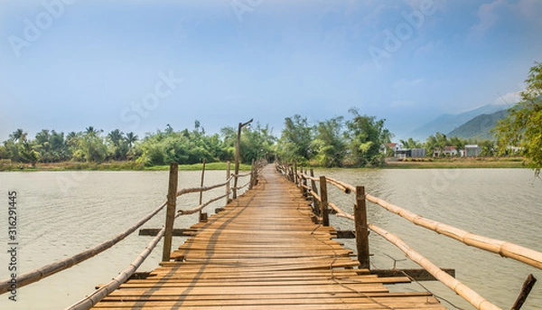 Obraz First-person view of a wooden and not safe railing bridge over the river in Vietnam.
