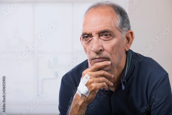Obraz Portrait of a senior man sitting with a bandage on his hand. (Health and fitness)