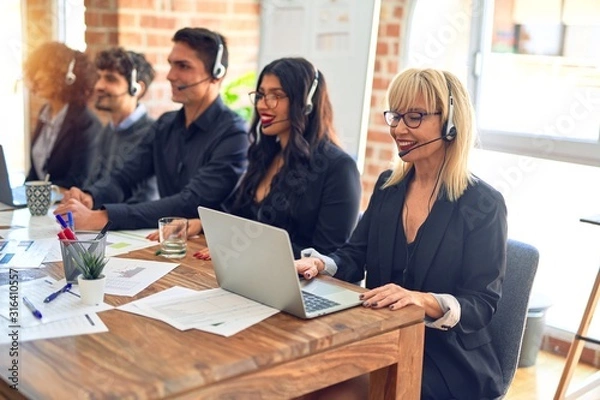 Fototapeta Group of call center workers smiling happy and confident. Working together with smile on face using headset at the office.