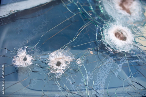 Fototapeta Bullet hole on a car windshield. Car window after a raid has a bullet hole. Broken glass. Bullet holes in a front windshield. Broken Windshield.