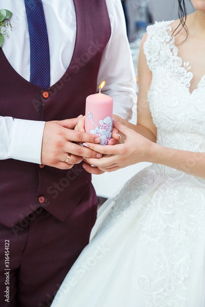 Fototapeta bride and groom lighting a candle together on a wedding day