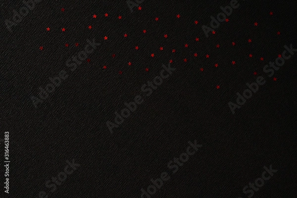 Fototapeta Red shiny stars on crepe paper with diagonal markings and a space for text. Black diagonal pattern for your creativity. Black pattern with shiny red stars.