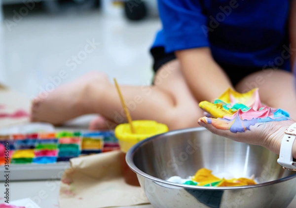 Fototapeta hands and kid working on slime making with colorful ingredient