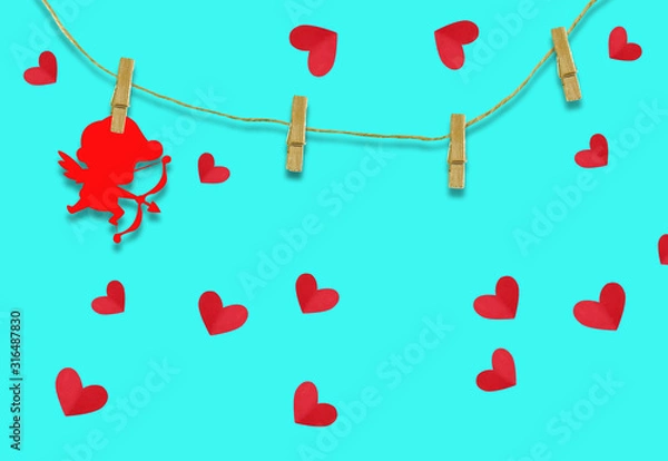Obraz The Valentine's day concept.The red cupid shaped card attached to a wooden clip Hanging with hemp rope on blue background.Valentine's Day background