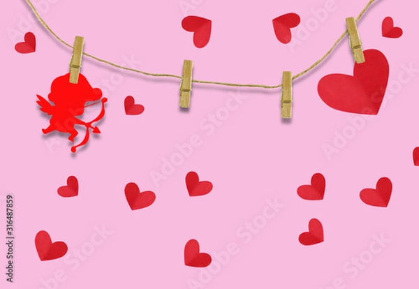 Obraz The Valentine's day concept.The red cupid shaped card attached to a wooden clip Hanging with hemp rope on pink background.Valentine's Day background
