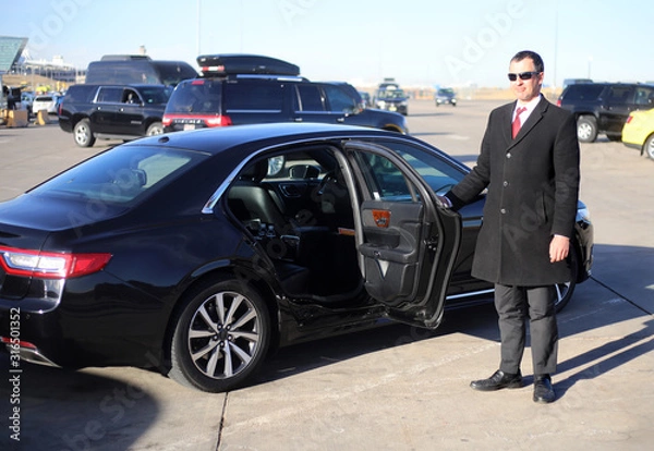 Fototapeta Chauffeur opens car's rear door