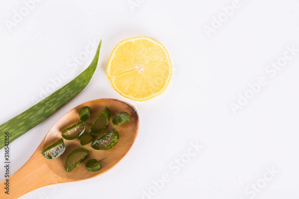 Fototapeta Aloe Vera świeże liście z plastrami i żelem na drewnianej łyżce. pojedynczo na białym. Aloes jest popularnym ziołem leczniczym używanym dla zdrowia i urody.
