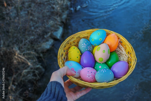 Obraz Bild von bunten Ostereiern in einem Korb und mir Fluss Hintergrund
