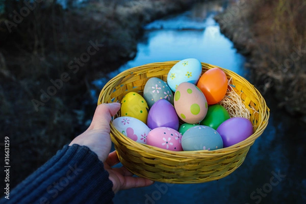 Obraz Bild von bunten Ostereiern in einem Korb und mir Fluss Hintergrund