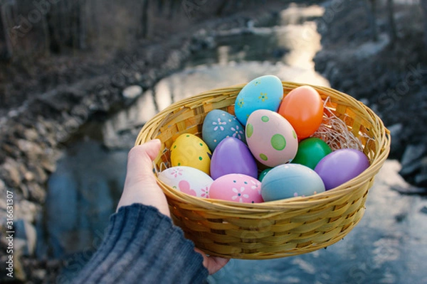 Obraz Bild von bunten Ostereiern in einem Korb und mir Fluss Hintergrund